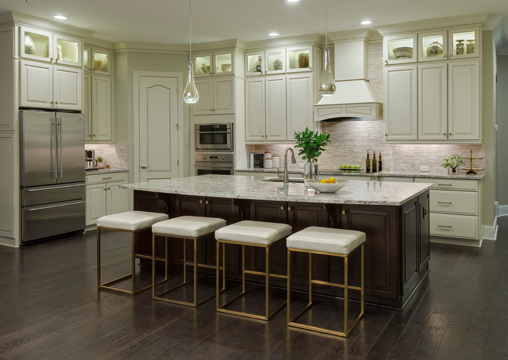 Inspiration for a mid-sized transitional l-shaped dark wood floor and brown floor open concept kitchen remodel in Los Angeles with a double-bowl sink, raised-panel cabinets, beige cabinets, granite countertops, beige backsplash, stone tile backsplash, stainless steel appliances and an island