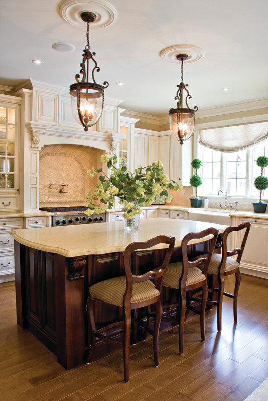 Inspiration for a large traditional u-shaped eat-in kitchen in Toronto with raised-panel cabinets, white cabinets, beige splashback, with island, an undermount sink, granite benchtops, limestone splashback, stainless steel appliances, medium hardwood floors and beige benchtop.