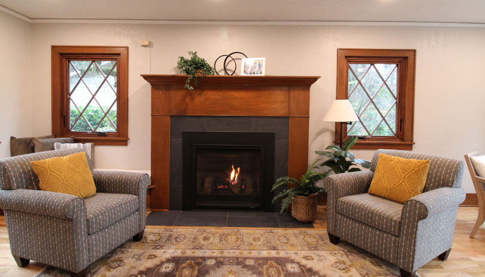 Mid-sized traditional enclosed living room in Seattle with a library, grey walls, light hardwood floors, a standard fireplace, a tile fireplace surround, no tv and brown floor.