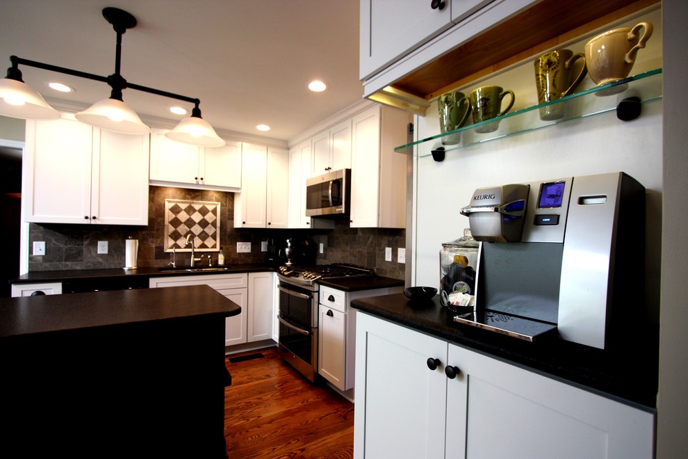 Inspiration for a mid-sized transitional l-shaped medium tone wood floor eat-in kitchen remodel in Raleigh with an undermount sink, shaker cabinets, white cabinets, granite countertops, gray backsplash, stone tile backsplash, stainless steel appliances and an island