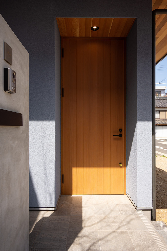 На фото: маленькая входная дверь в стиле модернизм с синими стенами, полом из керамической плитки, одностворчатой входной дверью, входной дверью из дерева среднего тона, серым полом и деревянным потолком для на участке и в саду