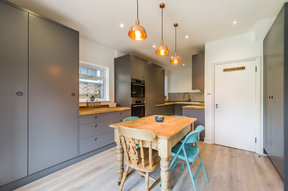 Foto på ett litet funkis kök och matrum, med släta luckor, grå skåp, grått stänkskydd, stänkskydd i cementkakel och ljust trägolv