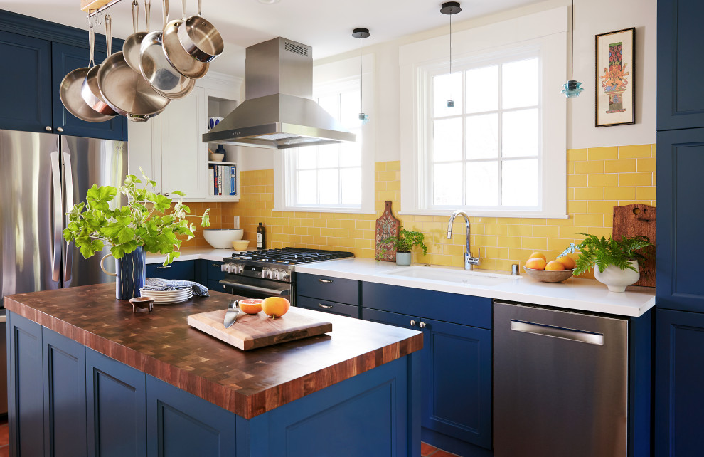 Mid-sized traditional l-shaped eat-in kitchen in San Francisco with an undermount sink, blue cabinets, yellow splashback, ceramic splashback, stainless steel appliances, with island, orange floor and white benchtop.