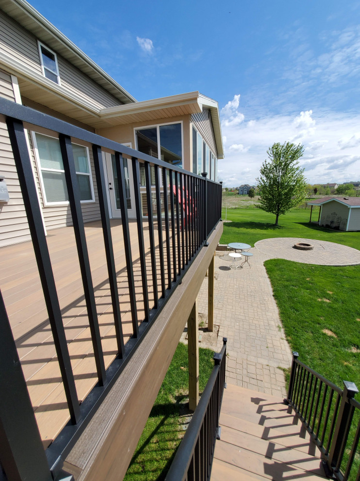 Large backyard second story metal railing deck photo with a roof extension