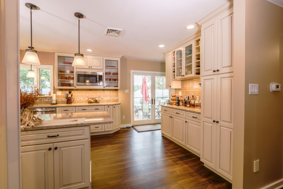 Eat-in kitchen - mid-sized transitional u-shaped vinyl floor and brown floor eat-in kitchen idea with an undermount sink, raised-panel cabinets, beige cabinets, quartz countertops, brown backsplash, porcelain backsplash, stainless steel appliances and an island