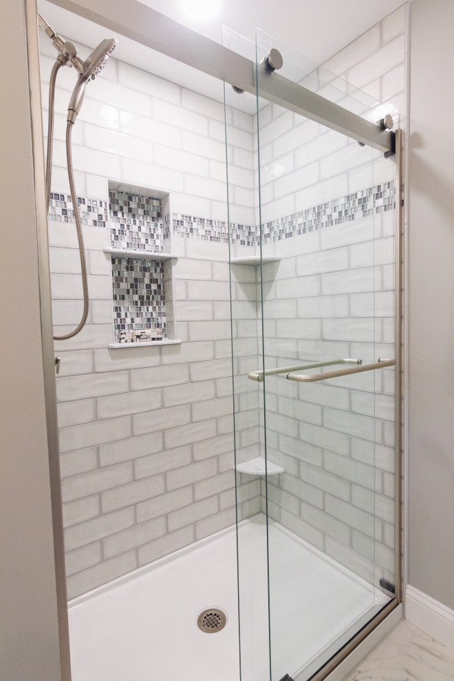 Example of a mid-sized transitional master green tile and ceramic tile porcelain tile, white floor and double-sink sliding shower door design with shaker cabinets, gray cabinets, a two-piece toilet, an undermount sink, quartz countertops, white countertops, a niche and a built-in vanity