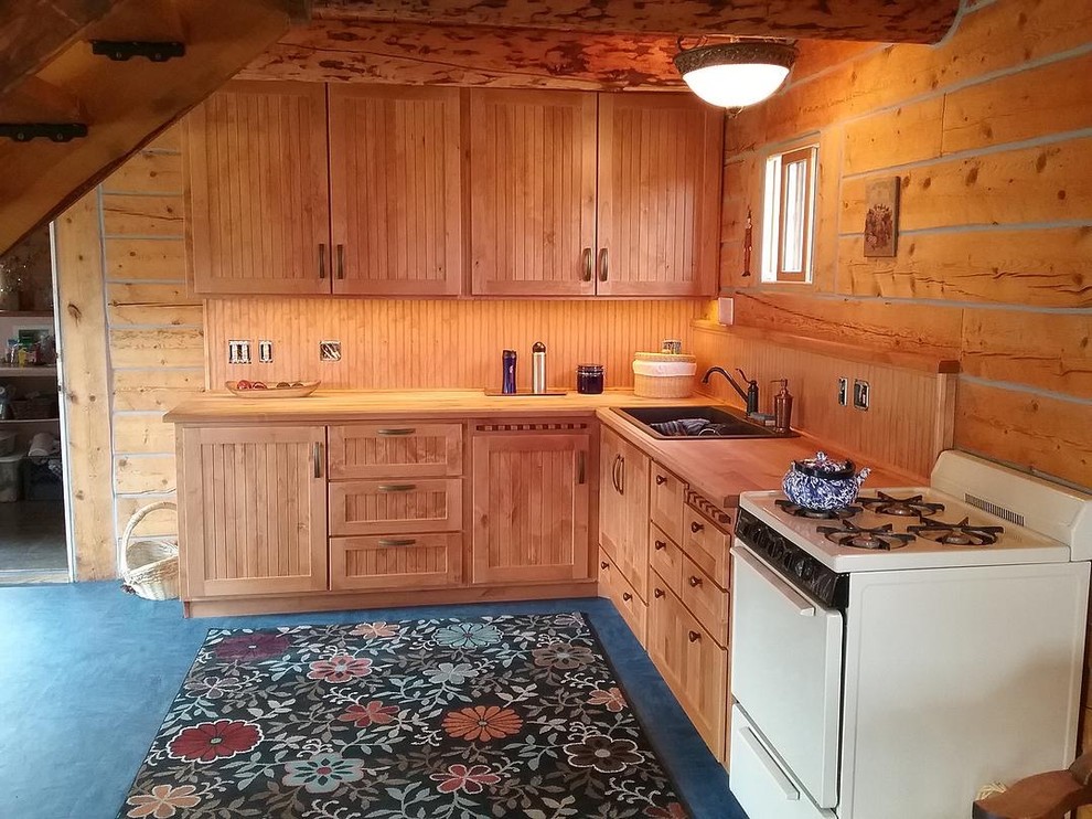 Mid-sized country l-shaped eat-in kitchen in Denver with a double-bowl sink, shaker cabinets, medium wood cabinets, wood benchtops, white appliances, carpet and no island.