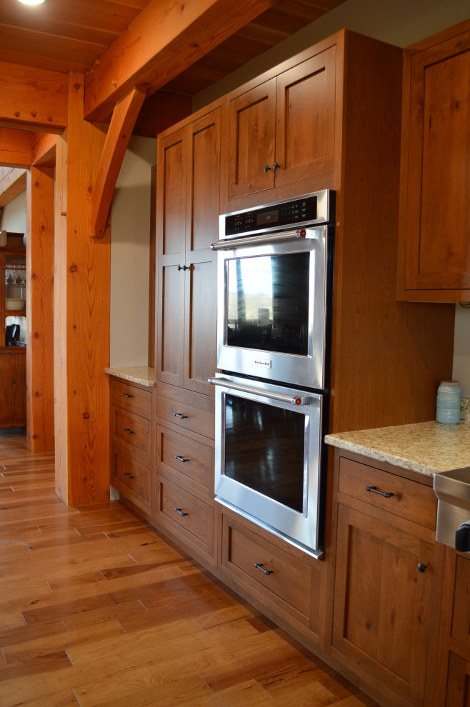 Inspiration for a mid-sized rustic u-shaped medium tone wood floor, brown floor and exposed beam eat-in kitchen remodel with a farmhouse sink, shaker cabinets, medium tone wood cabinets, paneled appliances and an island