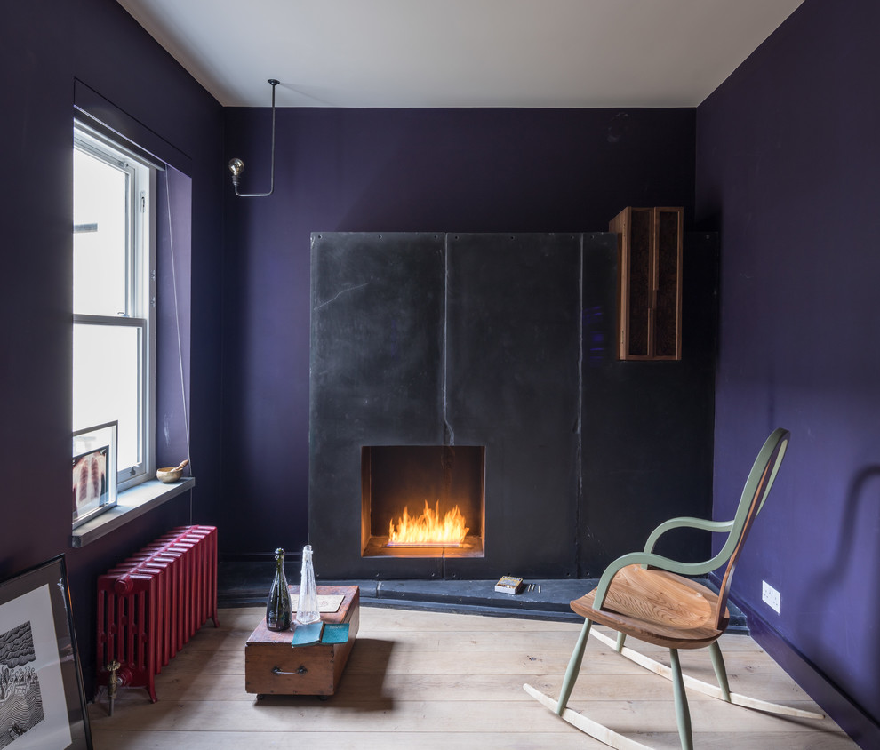 Design ideas for a mid-sized contemporary living room in London with a library, purple walls, light hardwood floors, a standard fireplace and a stone fireplace surround.