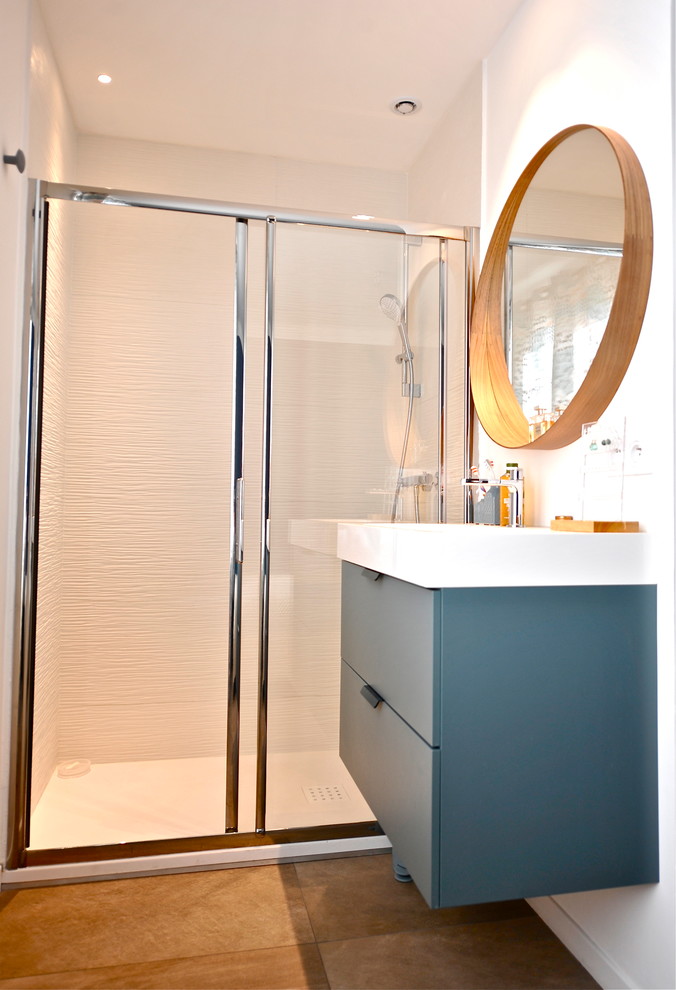 Design ideas for a small contemporary 3/4 bathroom in Nice with beaded inset cabinets, blue cabinets, an alcove shower, white tile, ceramic tile, ceramic floors, a wall-mount sink, solid surface benchtops, brown floor and a sliding shower screen.