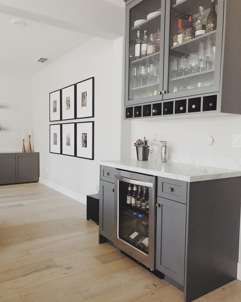 Classic l-shaped home bar in San Francisco with a submerged sink, shaker cabinets, grey cabinets, marble worktops, white splashback, ceramic splashback, light hardwood flooring, brown floors and white worktops.