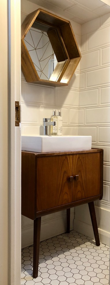 This is an example of a small midcentury powder room in Other with furniture-like cabinets, dark wood cabinets, a two-piece toilet, white tile, ceramic tile, multi-coloured walls, ceramic floors, a vessel sink, wood benchtops and white floor.