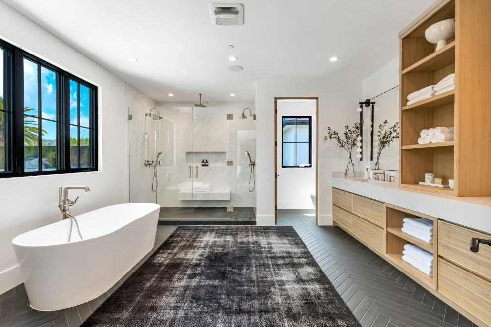 Photo of a rural ensuite bathroom in Los Angeles with louvered cabinets, light wood cabinets, a freestanding bath, a double shower, ceramic flooring, marble worktops, black floors, a hinged door, white worktops, an enclosed toilet, double sinks, a built in vanity unit and wallpapered walls.