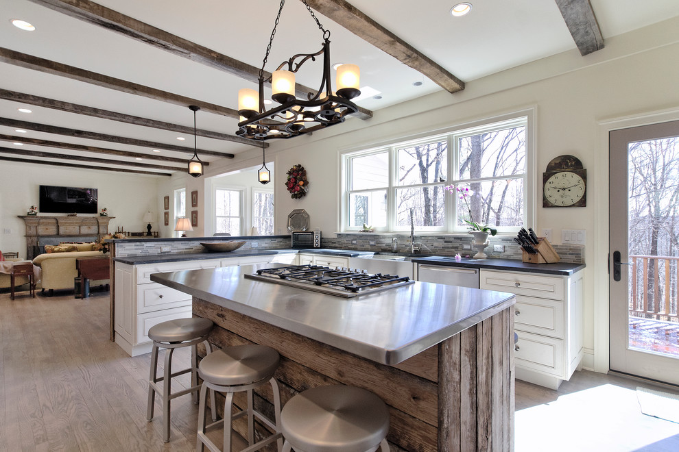 Inspiration for a transitional u-shaped open concept kitchen remodel with a farmhouse sink, raised-panel cabinets, white cabinets, soapstone countertops, multicolored backsplash and stainless steel appliances