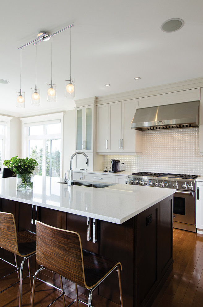 Inspiration for a large transitional l-shaped medium tone wood floor eat-in kitchen remodel with an undermount sink, recessed-panel cabinets, white cabinets, quartz countertops, white backsplash, porcelain backsplash, stainless steel appliances and an island