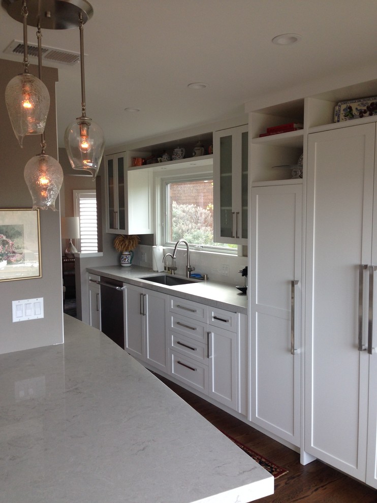 This is an example of a transitional galley eat-in kitchen in San Francisco with an undermount sink, flat-panel cabinets, white cabinets, quartz benchtops, white splashback, subway tile splashback, stainless steel appliances, dark hardwood floors and a peninsula.