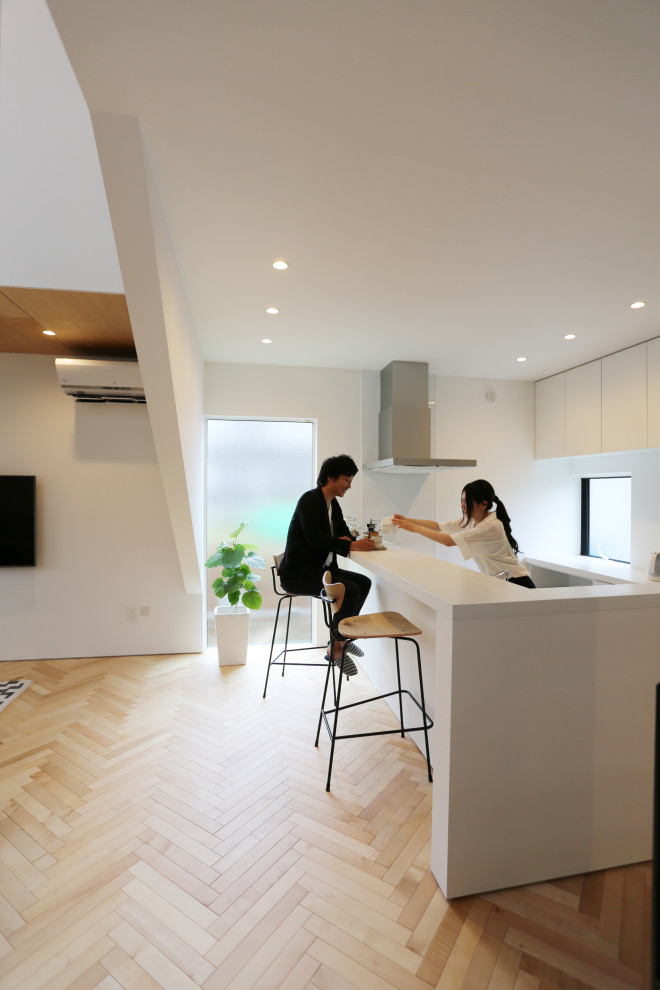 他の地域にある小さな北欧スタイルのおしゃれなダイニングキッチン (I型、一体型シンク、白いキャビネット、人工大理石カウンター、白いキッチンパネル、ガラス板のキッチンパネル、パネルと同色の調理設備、淡色無垢フローリング、ベージュの床、白いキッチンカウンター、クロスの天井) の写真