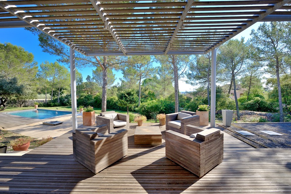 Large contemporary backyard deck in Montpellier with a container garden and a pergola.