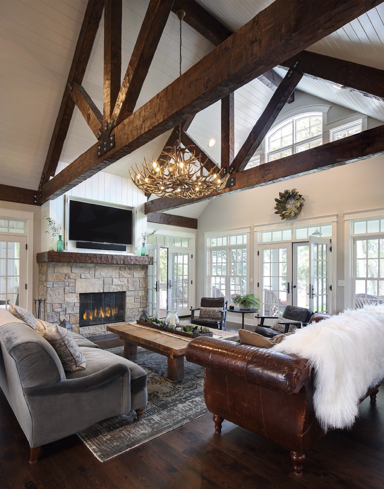 Mid-sized country open concept family room in Milwaukee with white walls, dark hardwood floors, a two-sided fireplace, a stone fireplace surround, a concealed tv and brown floor.