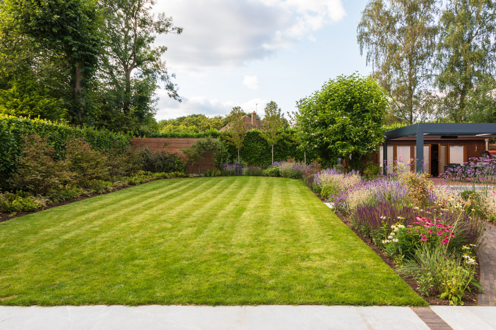 Geometrischer, Mittelgroßer Moderner Garten im Sommer, hinter dem Haus mit Rasenkanten, direkter Sonneneinstrahlung, Natursteinplatten und Holzzaun in Buckinghamshire
