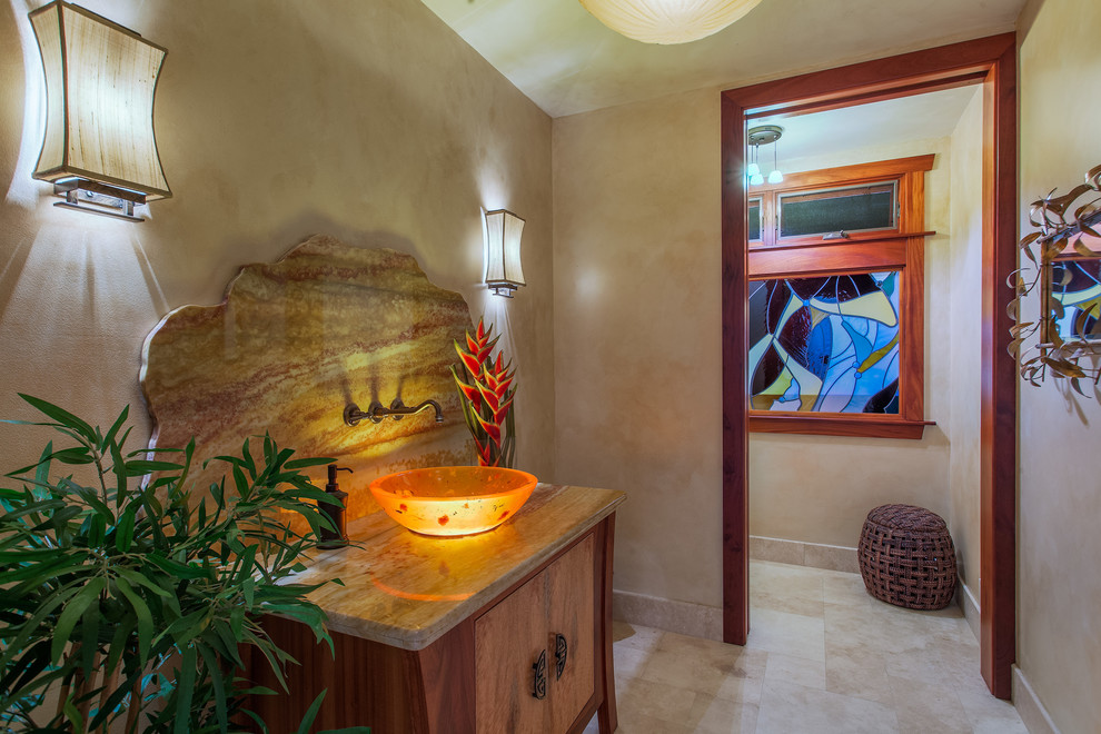 This is an example of a mid-sized tropical powder room in Hawaii with a vessel sink, flat-panel cabinets, medium wood cabinets, granite benchtops, beige tile, beige walls, travertine floors and stone slab.