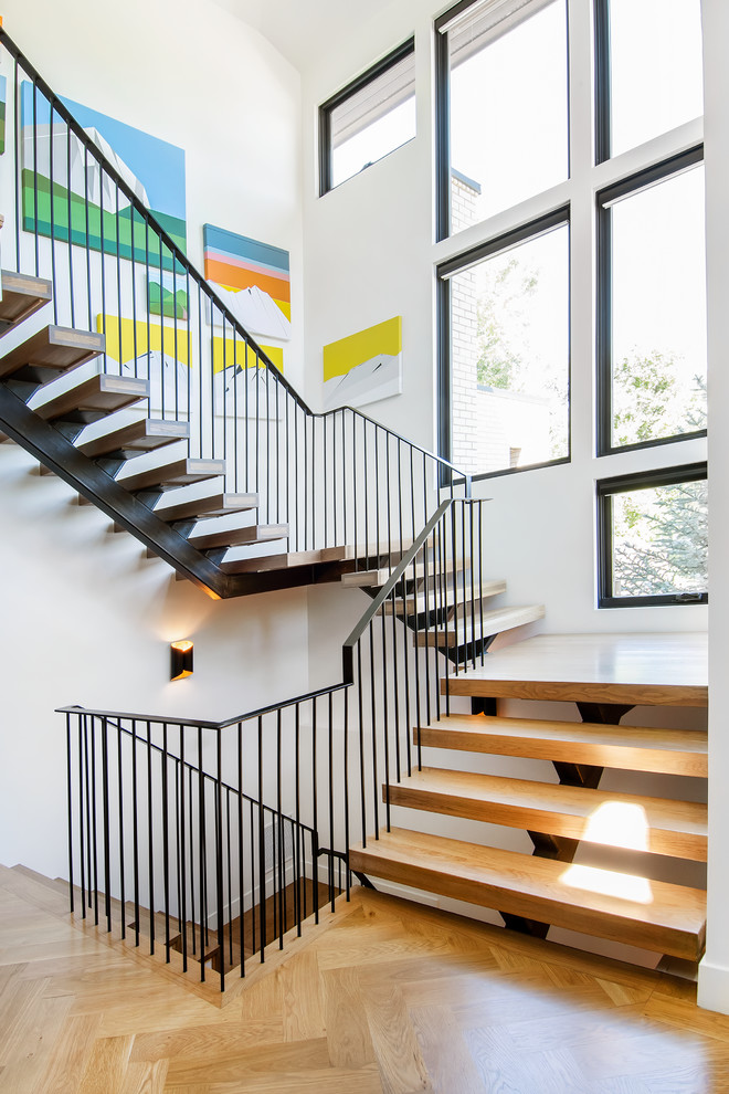 Photo of a midcentury wood floating staircase in Denver with open risers and metal railing.
