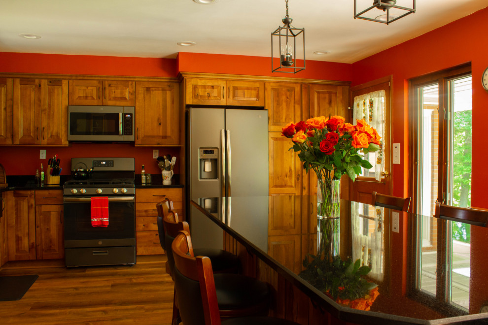 Inspiration for a large rustic u-shaped medium tone wood floor and brown floor open concept kitchen remodel with a farmhouse sink, raised-panel cabinets, medium tone wood cabinets, quartz countertops, stainless steel appliances, an island and black countertops