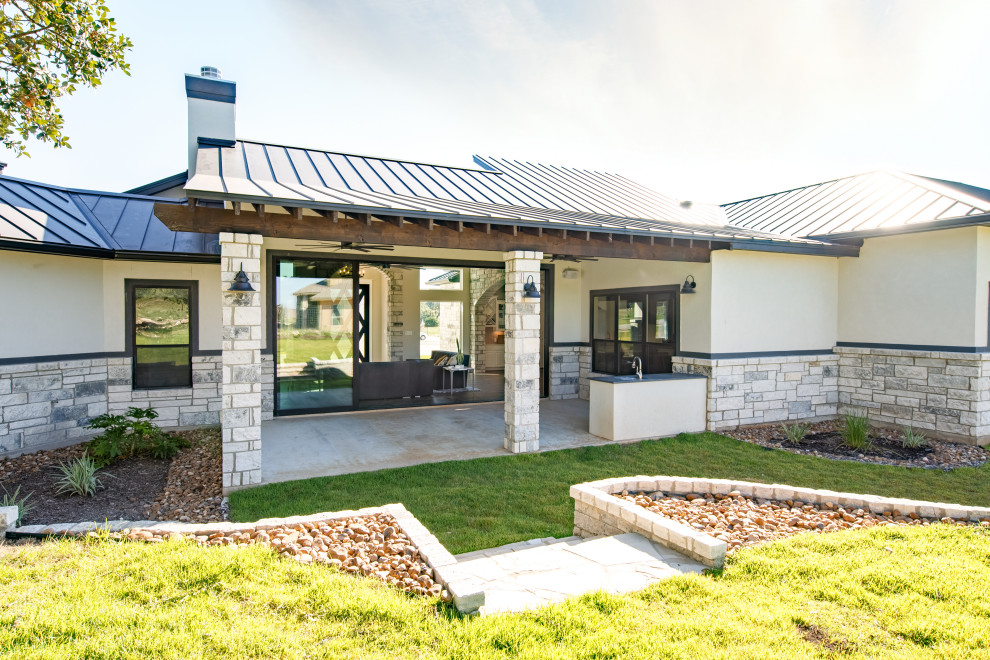 This is an example of a contemporary one-storey house exterior in Austin with a metal roof and a black roof.