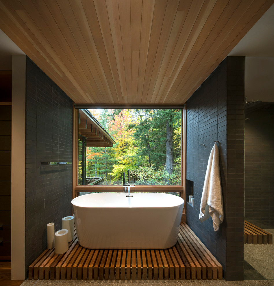 Contemporary master bathroom in Seattle with a freestanding tub, black walls and grey floor.