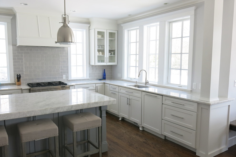 Open concept kitchen - mid-sized transitional u-shaped dark wood floor and brown floor open concept kitchen idea with an undermount sink, shaker cabinets, white cabinets, quartzite countertops, gray backsplash, ceramic backsplash, stainless steel appliances, an island and white countertops