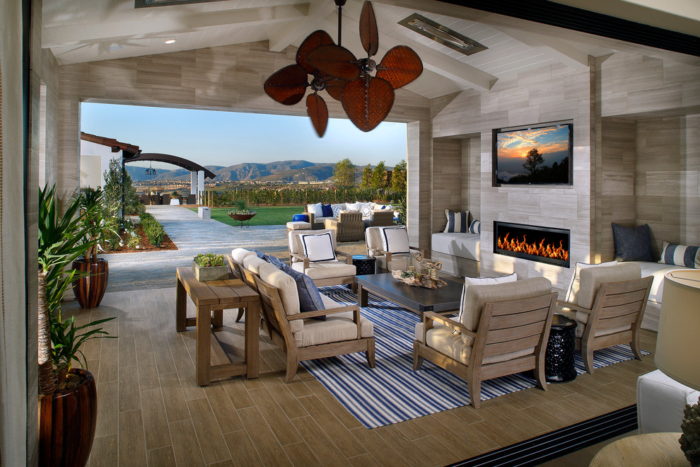 Photo of an expansive beach style backyard patio in San Diego with a fire feature, tile and a roof extension.