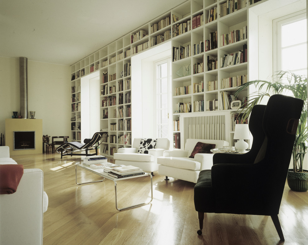Inspiration for a modern living room in Milan with a library, white walls and light hardwood floors.