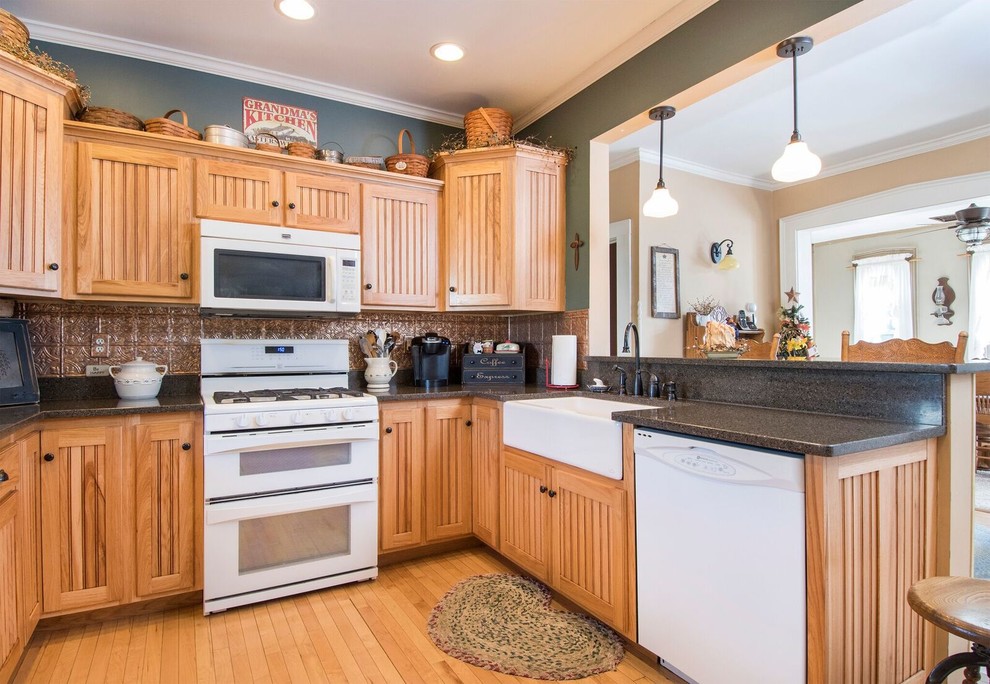 Eat-in kitchen - mid-sized rustic u-shaped light wood floor and brown floor eat-in kitchen idea in Cincinnati with a farmhouse sink, recessed-panel cabinets, light wood cabinets, granite countertops, metallic backsplash, ceramic backsplash, white appliances, a peninsula and gray countertops