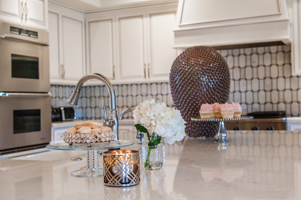 Inspiration for a large transitional single-wall travertine floor open concept kitchen remodel in Phoenix with a farmhouse sink, raised-panel cabinets, white cabinets, marble countertops, white backsplash, stone tile backsplash, stainless steel appliances and an island