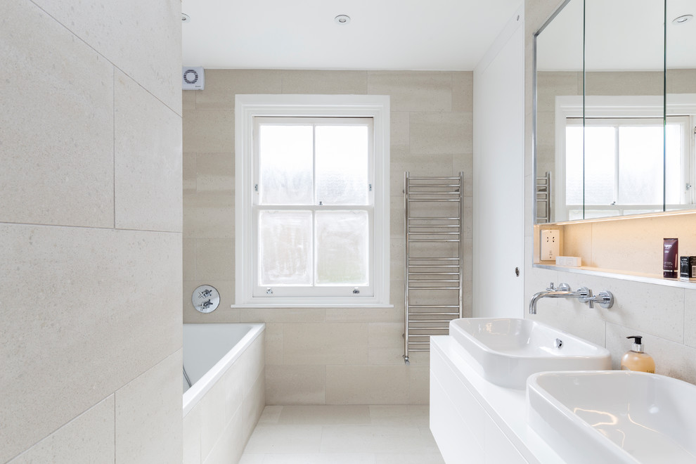 Inspiration for a small contemporary kids bathroom in London with flat-panel cabinets, white cabinets, a drop-in tub, an open shower, a wall-mount toilet, beige tile, porcelain tile, beige walls, porcelain floors, a drop-in sink, quartzite benchtops, beige floor and a sliding shower screen.