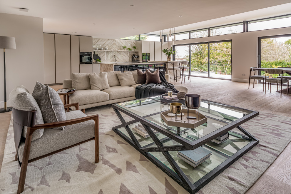 Inspiration for an expansive contemporary cream and black open plan living room in Hertfordshire with beige walls, light hardwood flooring and feature lighting.