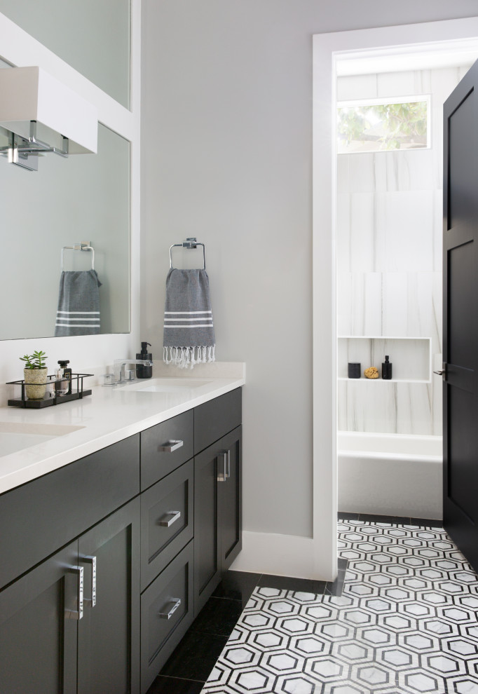 Transitional bathroom in Austin with shaker cabinets, black cabinets, an alcove tub, a shower/bathtub combo, white tile, porcelain tile, grey walls, marble floors, an undermount sink, engineered quartz benchtops, multi-coloured floor, white benchtops, a double vanity and a built-in vanity.