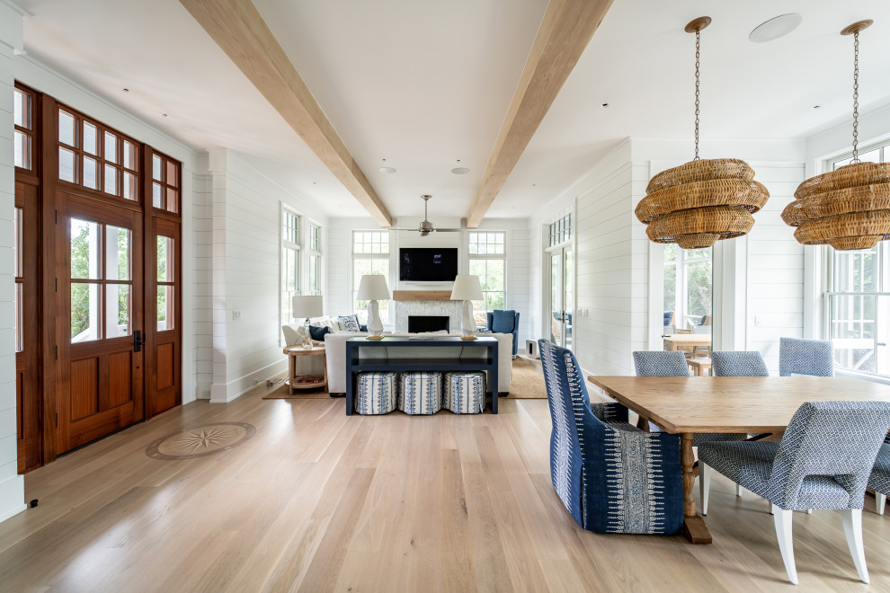 Beach style open plan dining room in Other with white walls, a standard fireplace, exposed beams and tongue and groove walls.