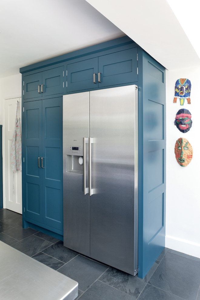 Inspiration for a mid-sized contemporary u-shaped eat-in kitchen in Surrey with an integrated sink, shaker cabinets, blue cabinets, stainless steel benchtops, metallic splashback, stainless steel appliances, slate floors and with island.