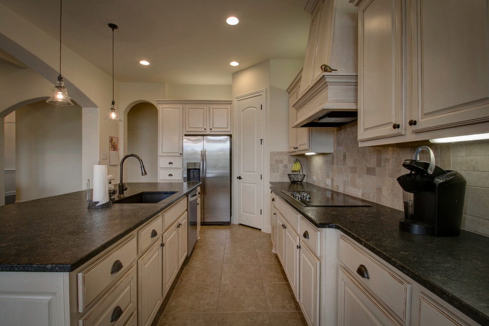 Inspiration for a rustic porcelain tile and beige floor kitchen pantry remodel in Austin with an undermount sink, raised-panel cabinets, white cabinets, granite countertops, beige backsplash, travertine backsplash, stainless steel appliances, an island and black countertops