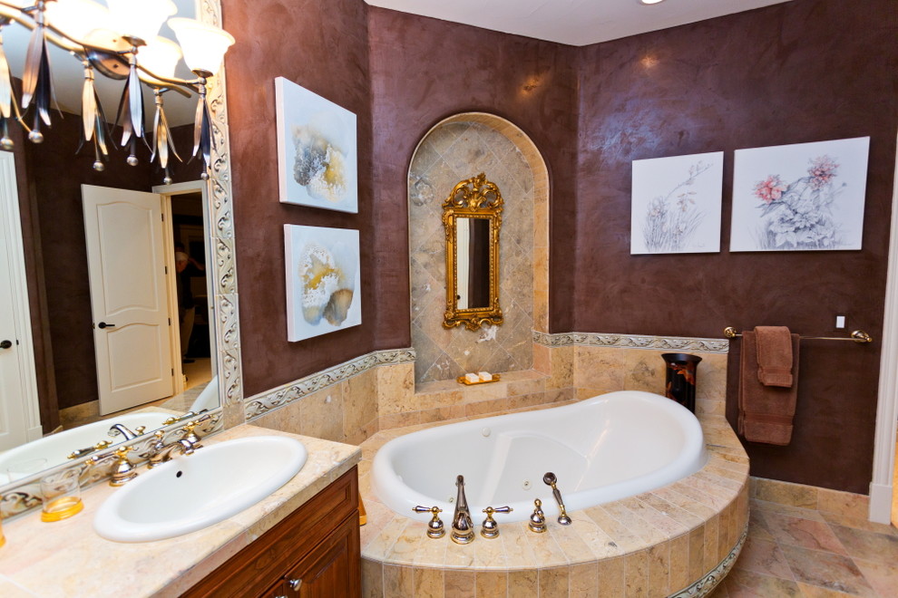 Large traditional master bathroom in Denver with a wall-mount sink, medium wood cabinets, marble benchtops, a corner tub, beige tile, brown walls and marble floors.