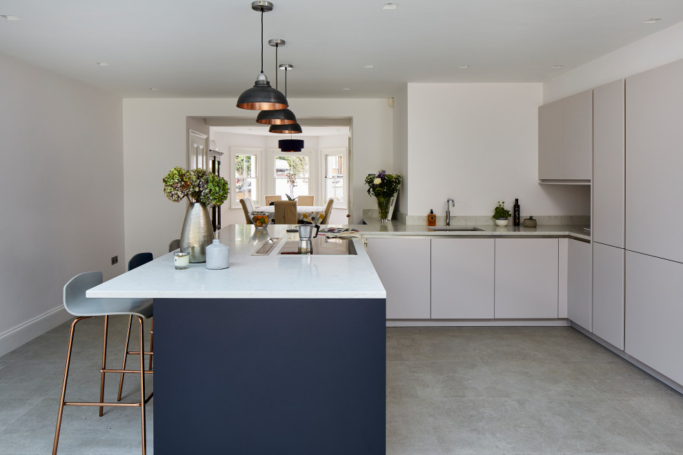 Inspiration for a large contemporary l-shaped open plan kitchen in London with a single-bowl sink, flat-panel cabinets, white cabinets, marble worktops, white appliances, a breakfast bar, white worktops and a coffered ceiling.