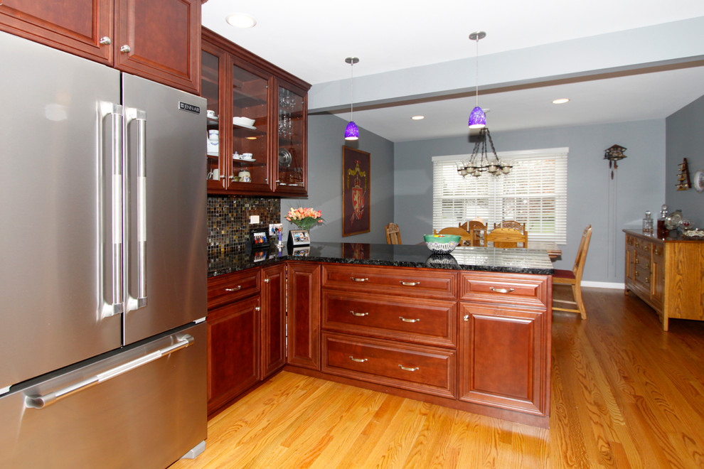 Inspiration for a mid-sized transitional u-shaped medium tone wood floor eat-in kitchen remodel in Chicago with an undermount sink, raised-panel cabinets, medium tone wood cabinets, granite countertops, multicolored backsplash, glass tile backsplash, stainless steel appliances and a peninsula