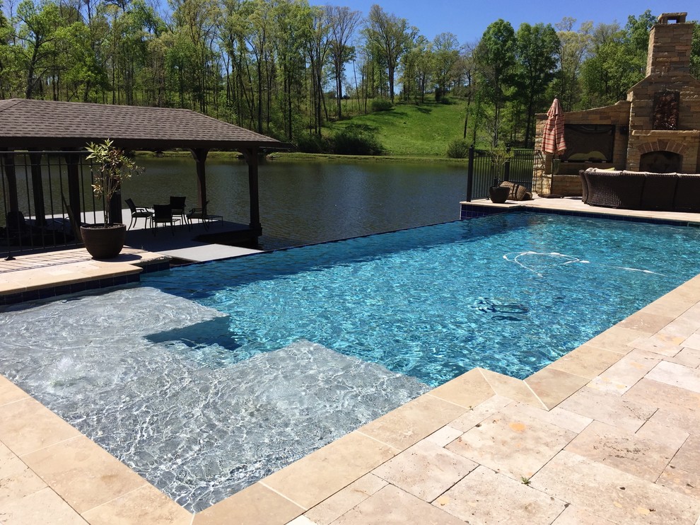This is an example of a backyard rectangular infinity pool in Birmingham with natural stone pavers.