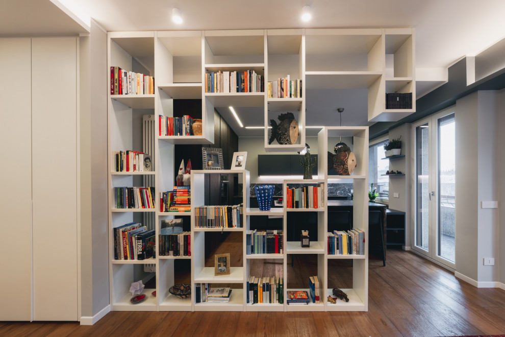 This is an example of a large contemporary open concept living room in Milan with a library, grey walls, light hardwood floors, a built-in media wall, brown floor and recessed.