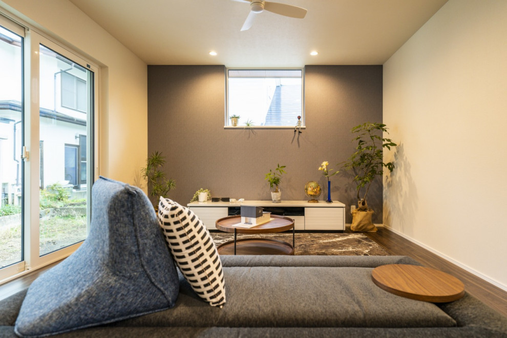 他の地域にあるお手頃価格の中くらいなモダンスタイルのおしゃれなLDK (黒い壁、濃色無垢フローリング、据え置き型テレビ、茶色い床、クロスの天井、壁紙、アクセントウォール、白い天井) の写真