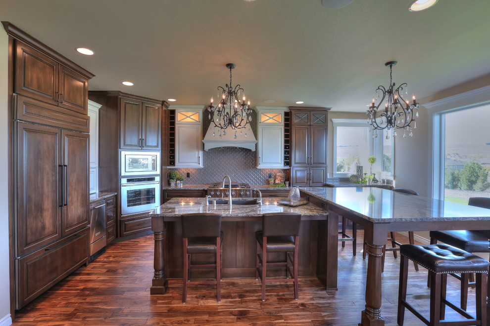 Example of a large transitional l-shaped medium tone wood floor eat-in kitchen design in Seattle with an undermount sink, medium tone wood cabinets, granite countertops, brown backsplash, stainless steel appliances and an island