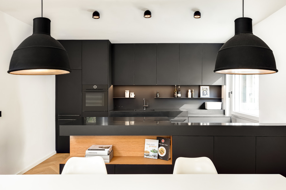 Inspiration for a modern single-wall eat-in kitchen in Munich with flat-panel cabinets, black cabinets, black splashback, medium hardwood floors, with island and brown floor.