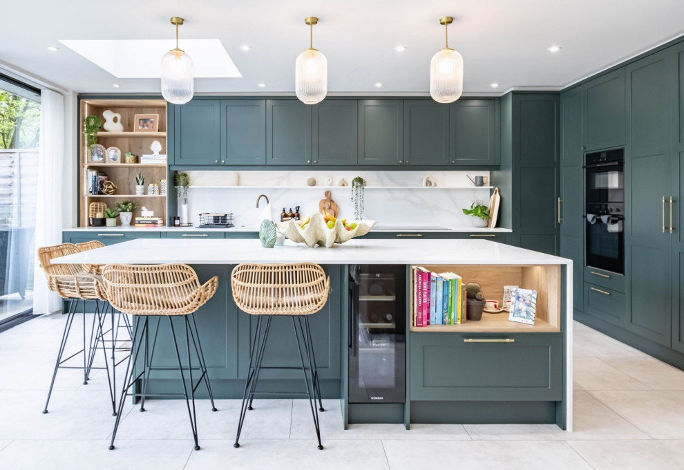 Design ideas for a large transitional l-shaped eat-in kitchen in London with an undermount sink, shaker cabinets, green cabinets, quartzite benchtops, white splashback, black appliances, ceramic floors, with island, grey floor and white benchtop.