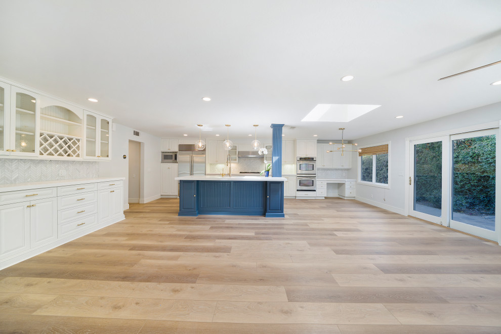 Mid-sized transitional laminate floor and brown floor eat-in kitchen photo in Orange County with an undermount sink, shaker cabinets, blue cabinets, quartz countertops, white backsplash, mosaic tile backsplash, stainless steel appliances, an island and white countertops